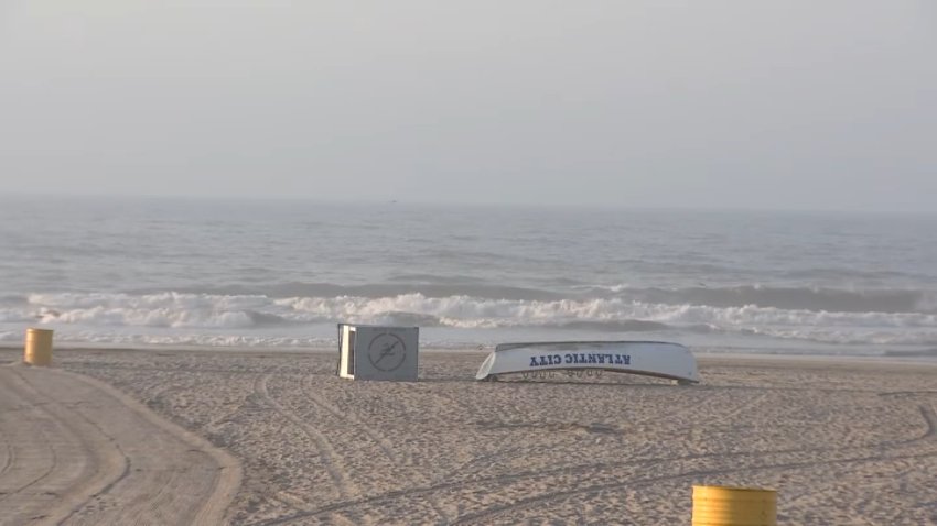 lifeguard boat with "Atlantic City" on it is on a sandy beach in front of the Atlantic Ocean.