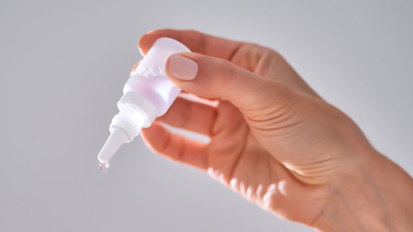 Women’s hands with a bottle of drops for the nose or eyes.