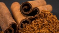 Cinnamon sticks with cinnamon powder on stone plate background