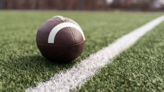 American football ball on green grass field background.