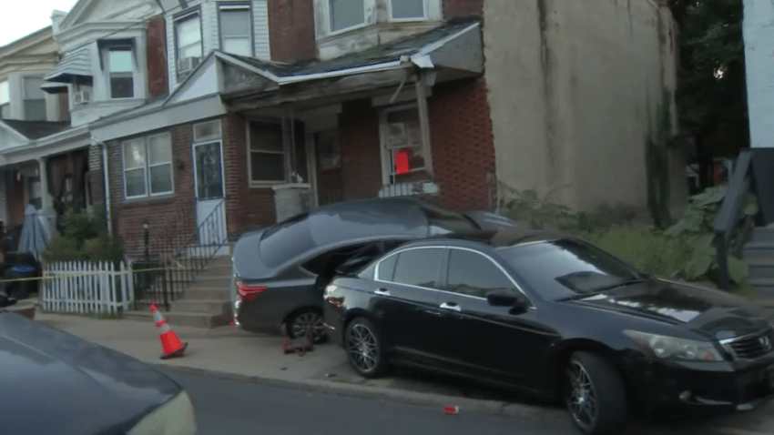 Car wedged between rowhome and another car.